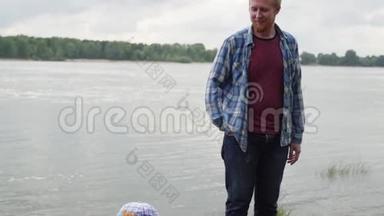 一个人和他的儿子在湖边散步。 爸爸和他的儿子在河边散步。 一个人蹲在他儿子面前。